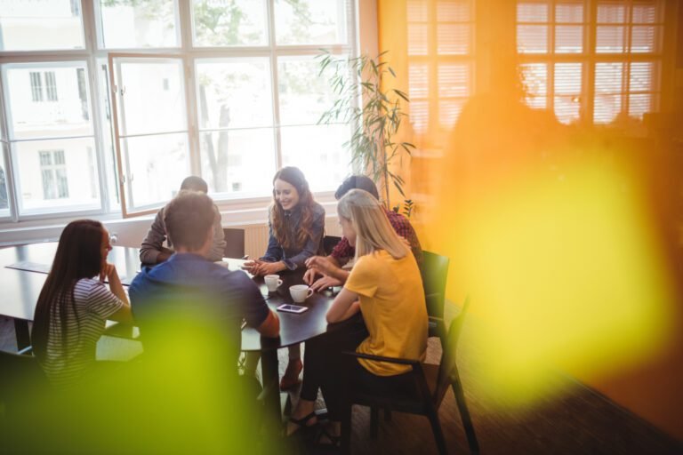 Business executives interacting with each other while having coffee in office