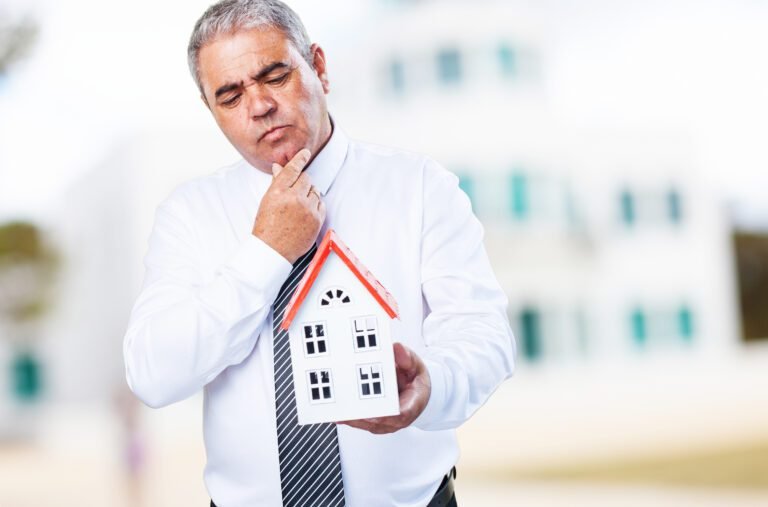 worried mature man holding a house