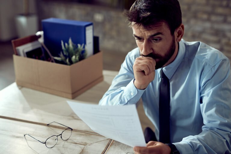 Worried businessman going through paperwork after losing his job in the office.